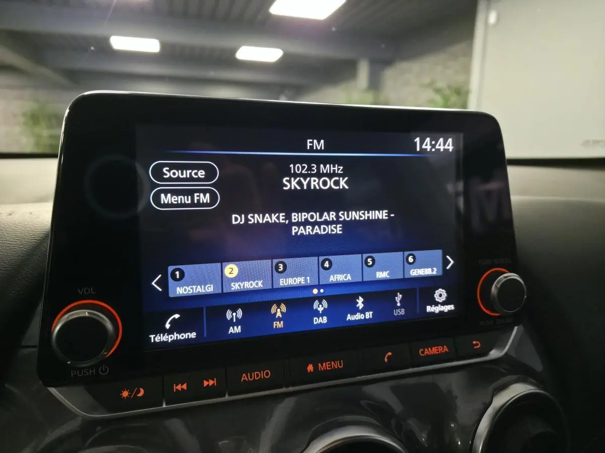Écran tactile central du Nissan Juke 2024 affichant la radio FM Skyrock, avec commandes audio et bouton caméra.