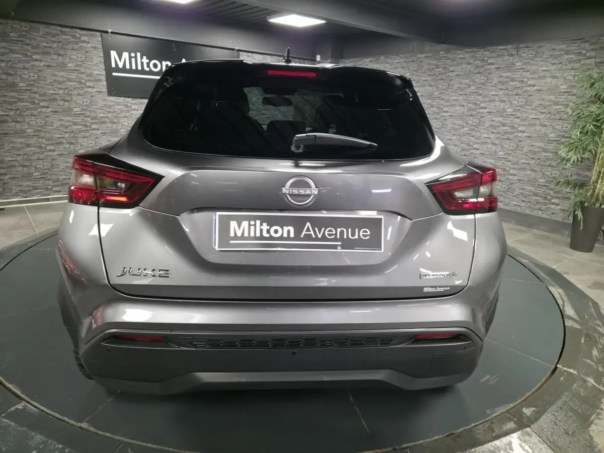 Vue arrière d'un Nissan Juke gris métallisé 2024 avec logo Hybrid et feux arrière LED distinctifs.