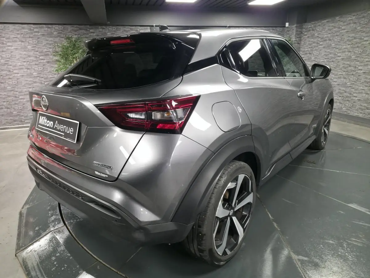 Vue 3/4 arrière droite du Nissan Juke 1.6 Hybrid gris métallisé avec jantes alliage 19 pouces et toit noir.