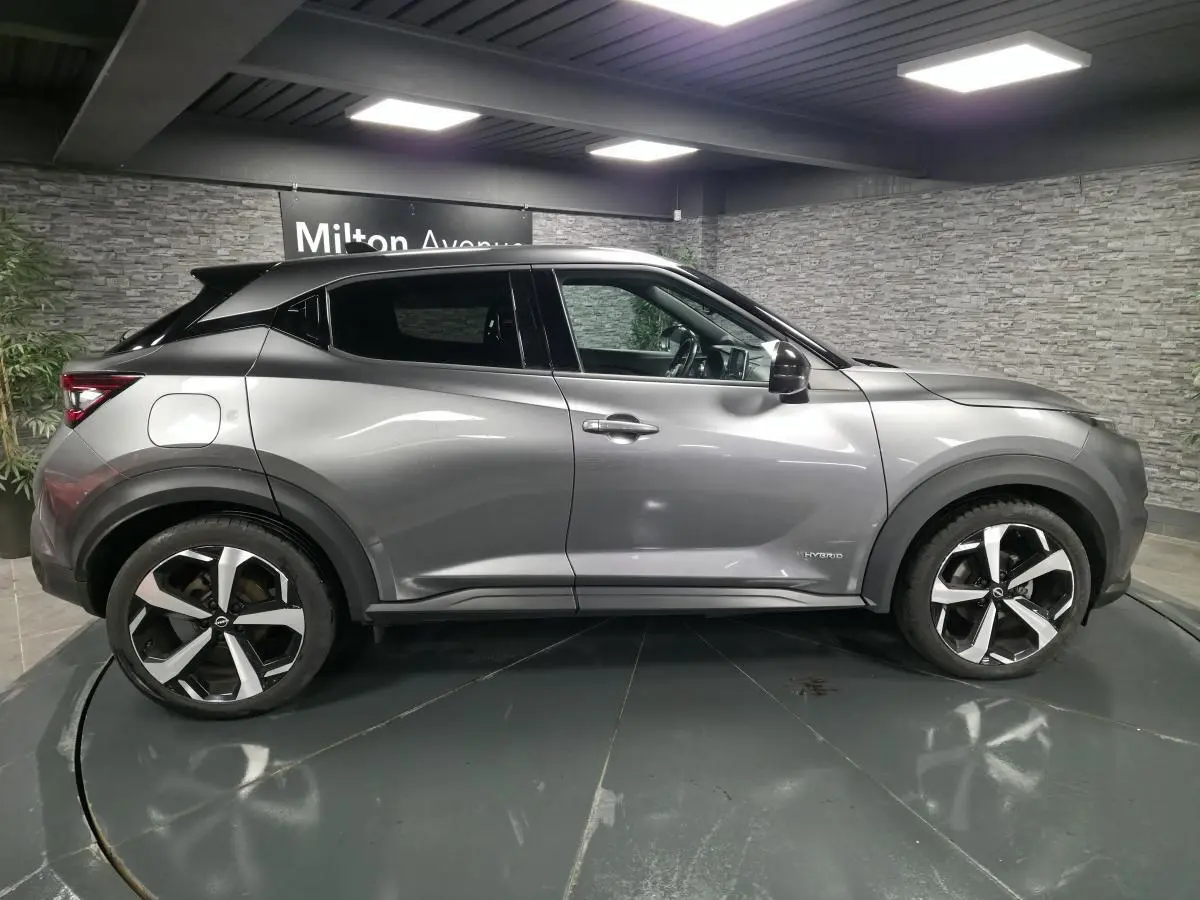 Vue de profil côté gauche du Nissan Juke 1.6 Hybrid gris métallisé avec jantes alliage 19 pouces et badge Hybrid.