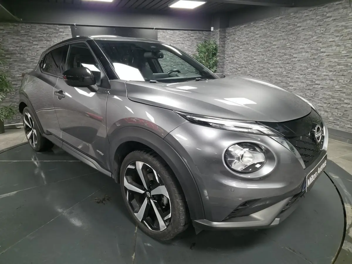 Nissan Juke gris métallisé en 3/4 avant droit, avec jantes alliage noires et toit noir contrasté.