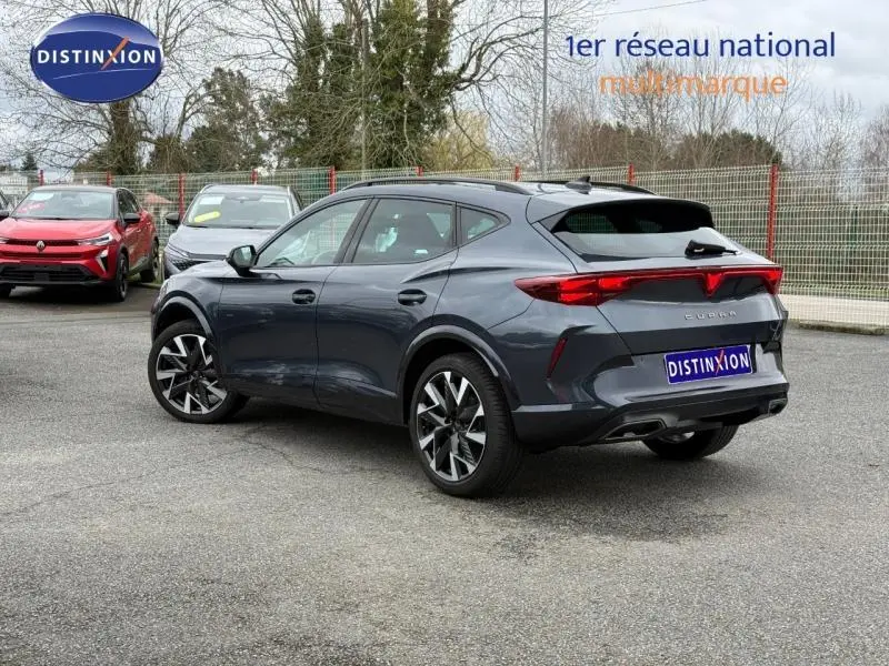 Vue 3/4 arrière droite d'une CUPRA Formentor 1.5 eTSI Hybrid 2025 en gris magnétique mat avec feux arrière LED allumés.