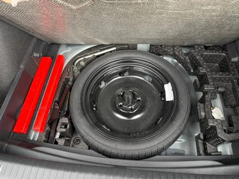 Vue plongeante sur la roue de secours noire et les outils de bord dans le coffre d'une CUPRA Formentor 1.5 eTSI Hybrid 2025.