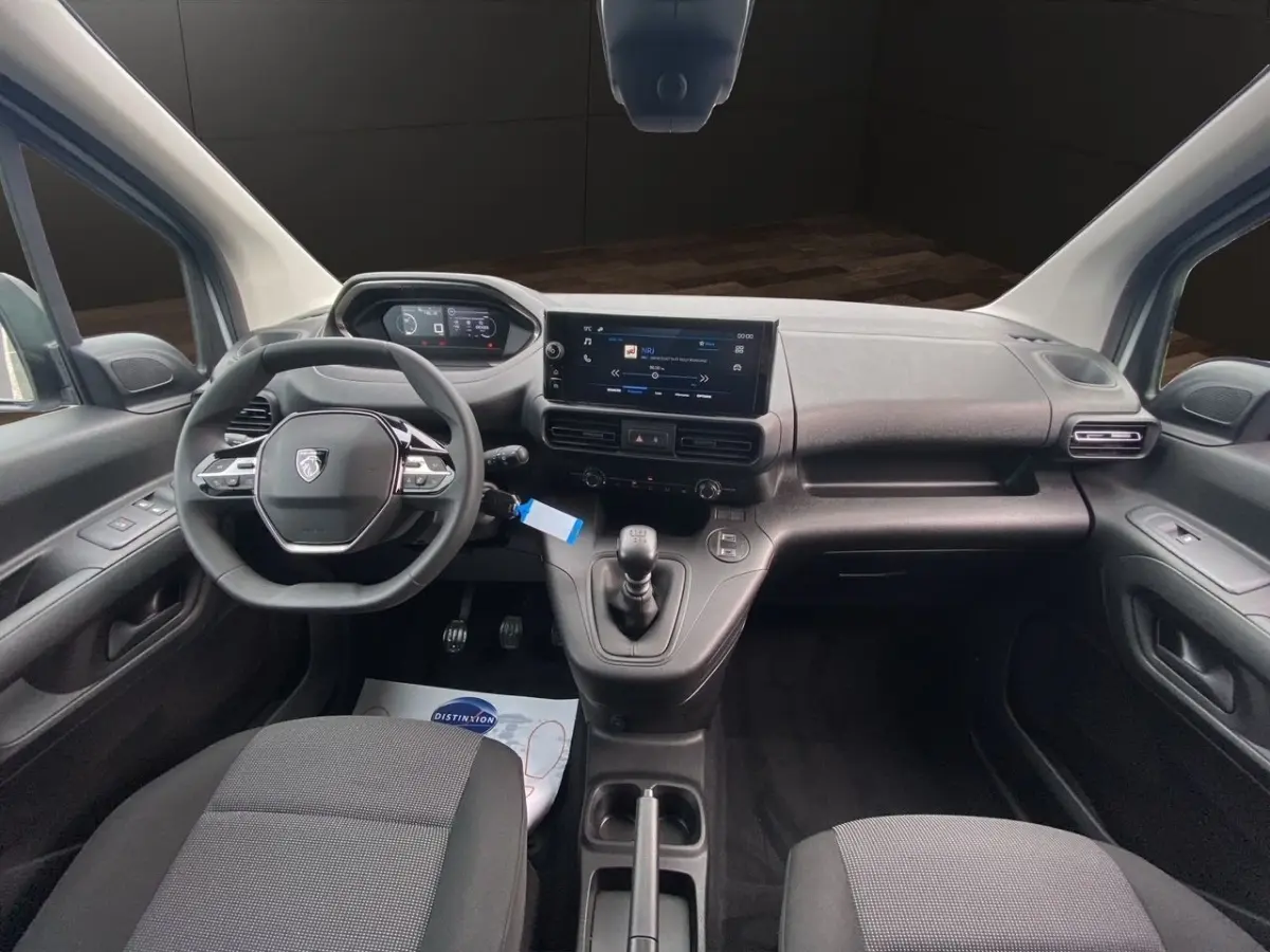 Vue intérieure avant du Peugeot Partner blanc 2024, tableau de bord avec écran tactile et volant multifonctions.