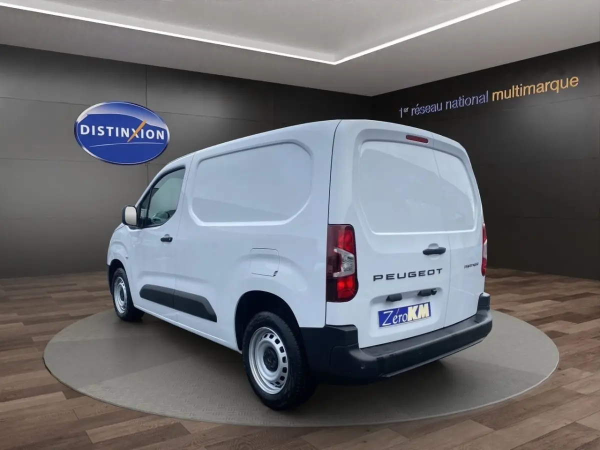 Vue 3/4 arrière droite d’un Peugeot Partner blanc, fourgon utilitaire avec pare-chocs noir et jantes acier.