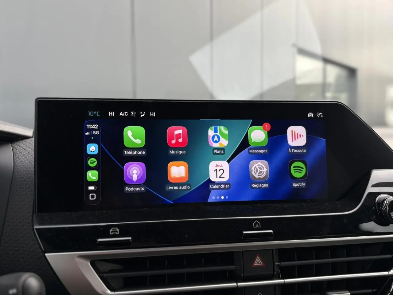 Écran tactile central de la Citroën C4 Hybrid 2025 affichant Apple CarPlay avec icônes colorées, ambiance intérieure moderne.