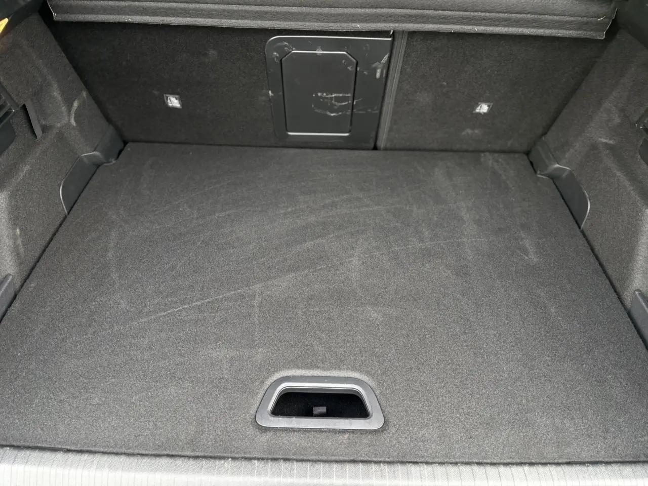 Vue intérieure du coffre spacieux et propre de la Citroën C4 Hybrid 2025 en gris Mercury, avec trappe d'accès au fond.