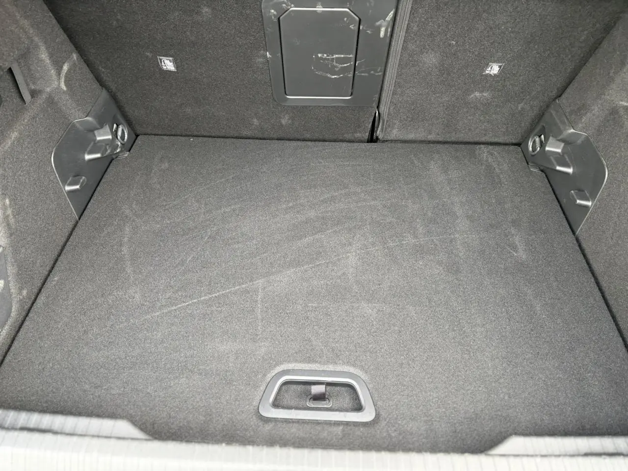 Coffre ouvert de Citroën C4 Hybrid 2025, vue intérieure montrant le tapis de sol noir et la trappe arrière.