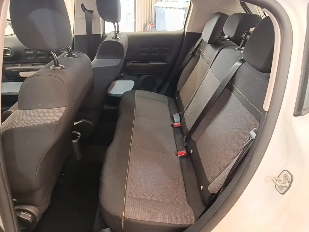 Vue intérieure côté droit de la banquette arrière grise du Citroën C3 blanc, avec appuie-têtes et ceintures visibles.