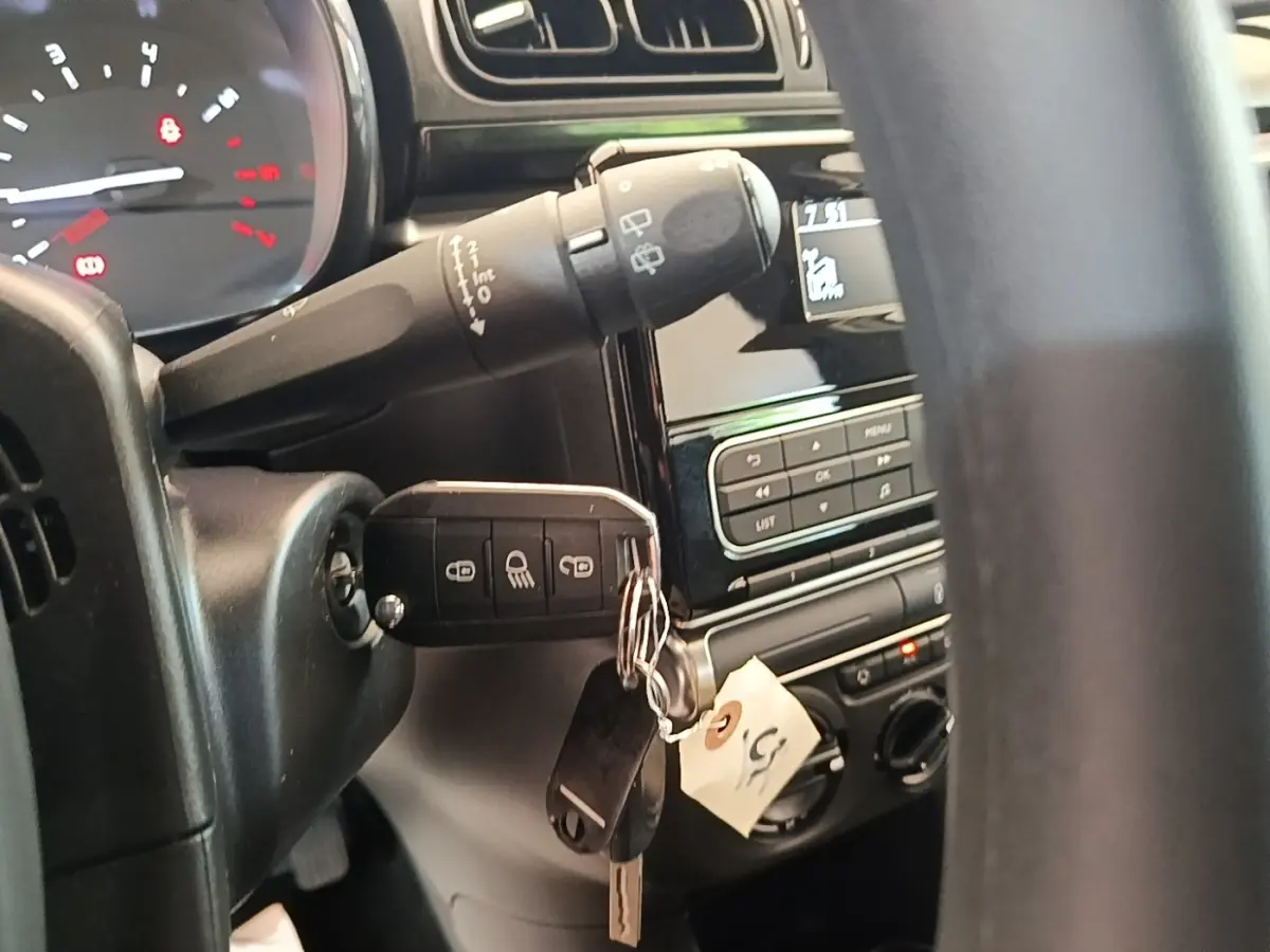 Vue rapprochée de l’intérieur côté conducteur d’une Citroën C3 blanche, clé insérée dans le contacteur avec tableau de bord partiel.