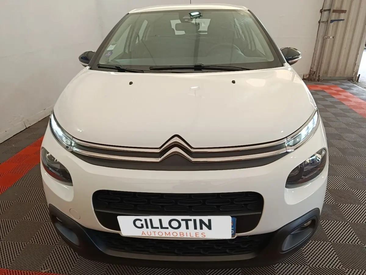 Vue avant d'une Citroën C3 blanche de 2019 avec calandre noire et phares LED allumés en intérieur.