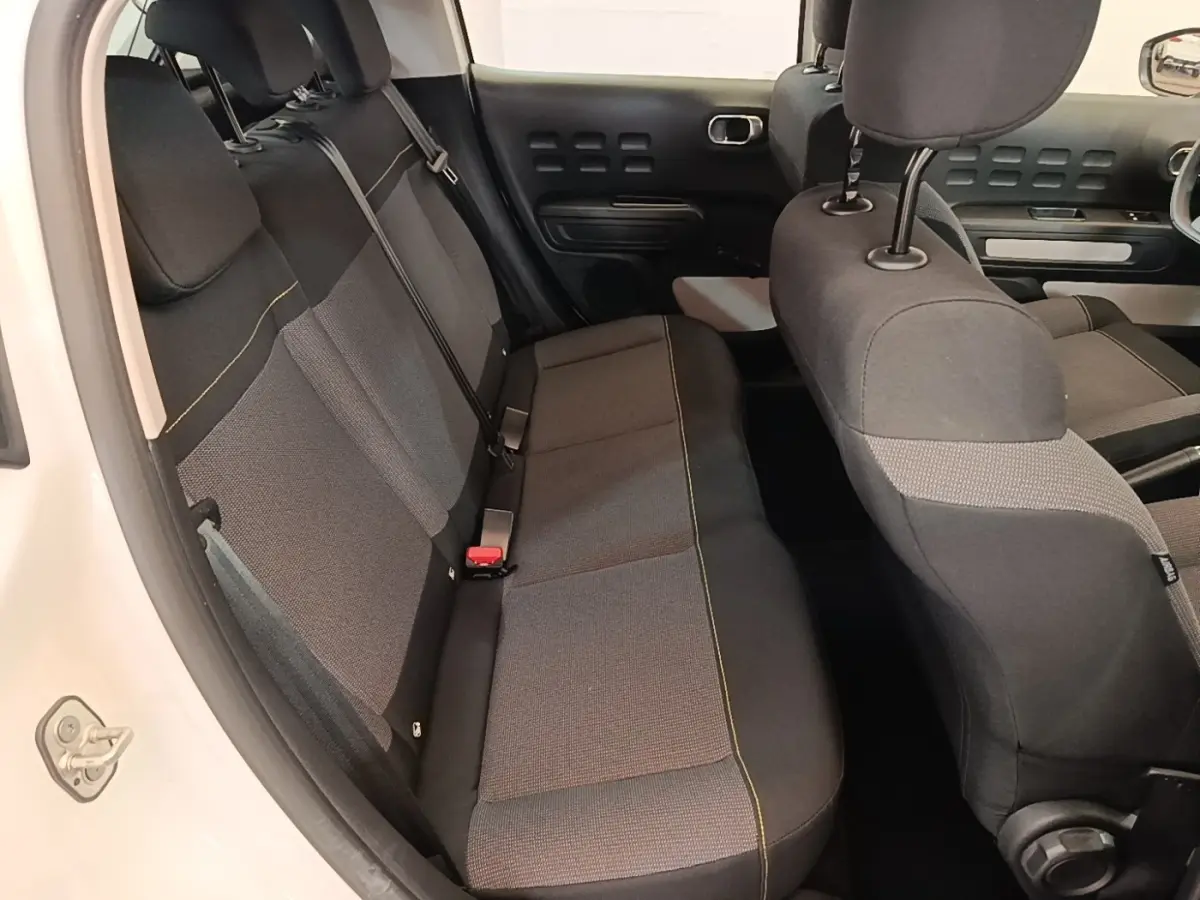 Vue intérieure côté arrière droit de la Citroën C3 blanche 2019, montrant la banquette arrière en tissu gris et noir.