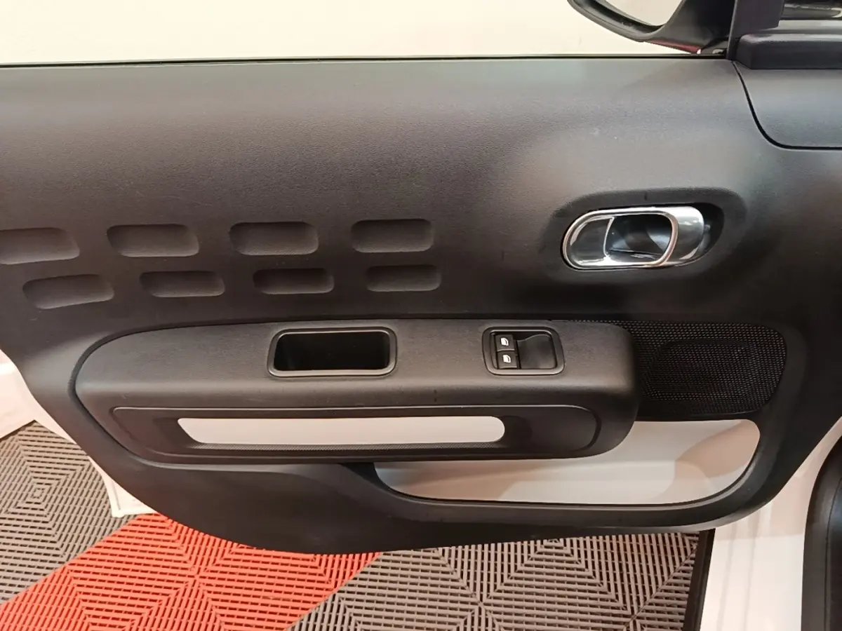 Vue intérieure de la porte avant gauche noire et blanche d'une Citroën C3 PureTech 110 Feel 2019.
