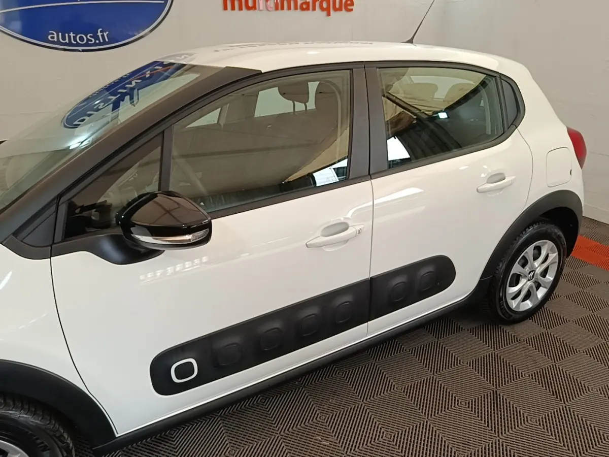 Vue latérale droite d'une Citroën C3 blanche avec protections latérales noires et rétroviseur noir brillant.