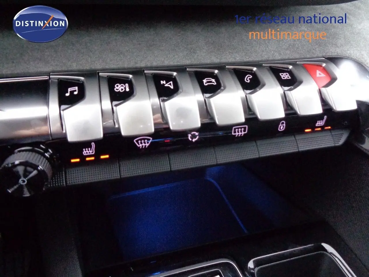 Gros plan sur la rangée de boutons argentés du tableau de bord du Peugeot 3008 gris platinium, avec éclairage orange des sièges chauffants.