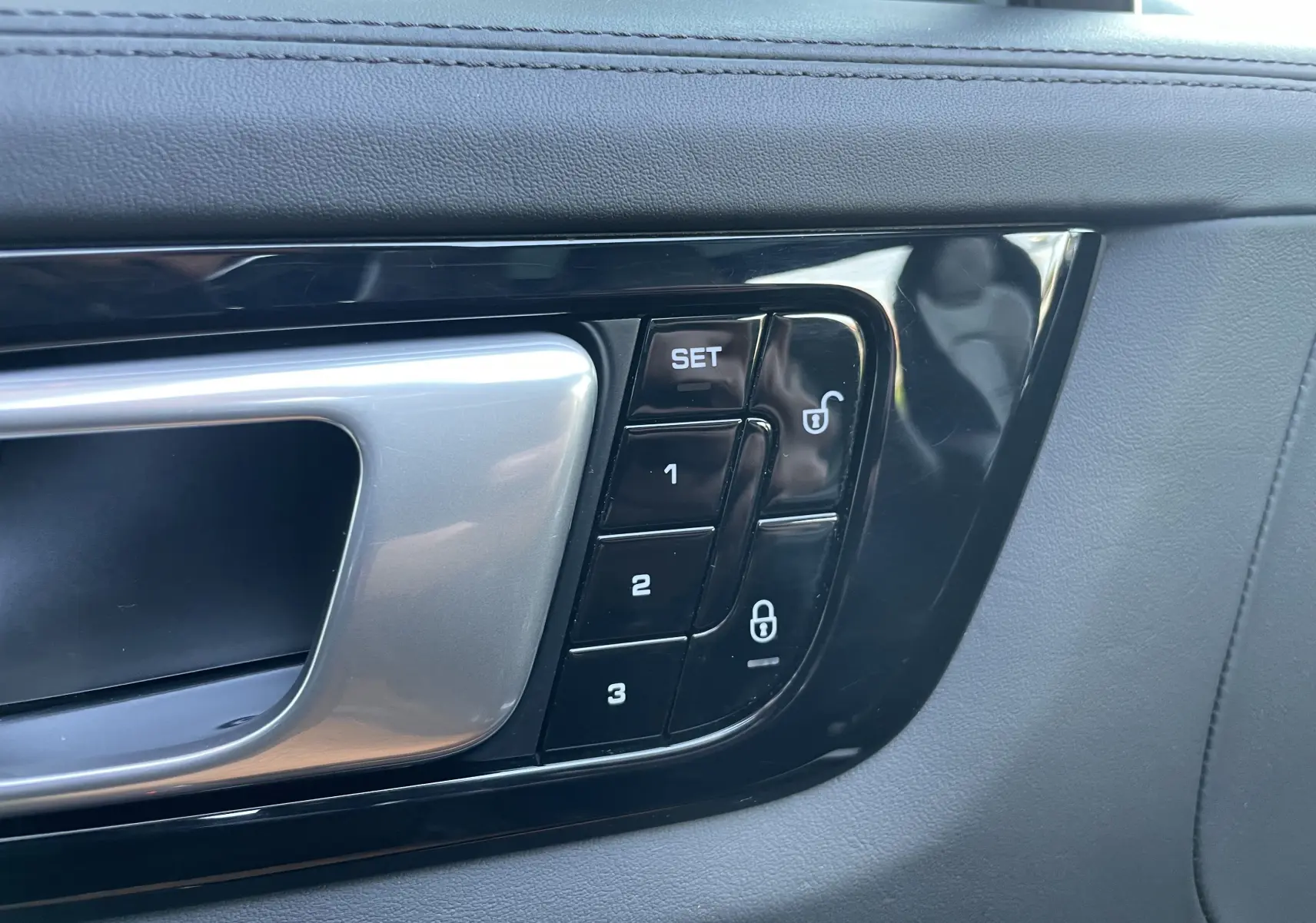 Gros plan sur la poignée intérieure côté gauche du Porsche Cayenne E-Hybrid 2018 avec boutons de réglage mémoire et verrouillage.
