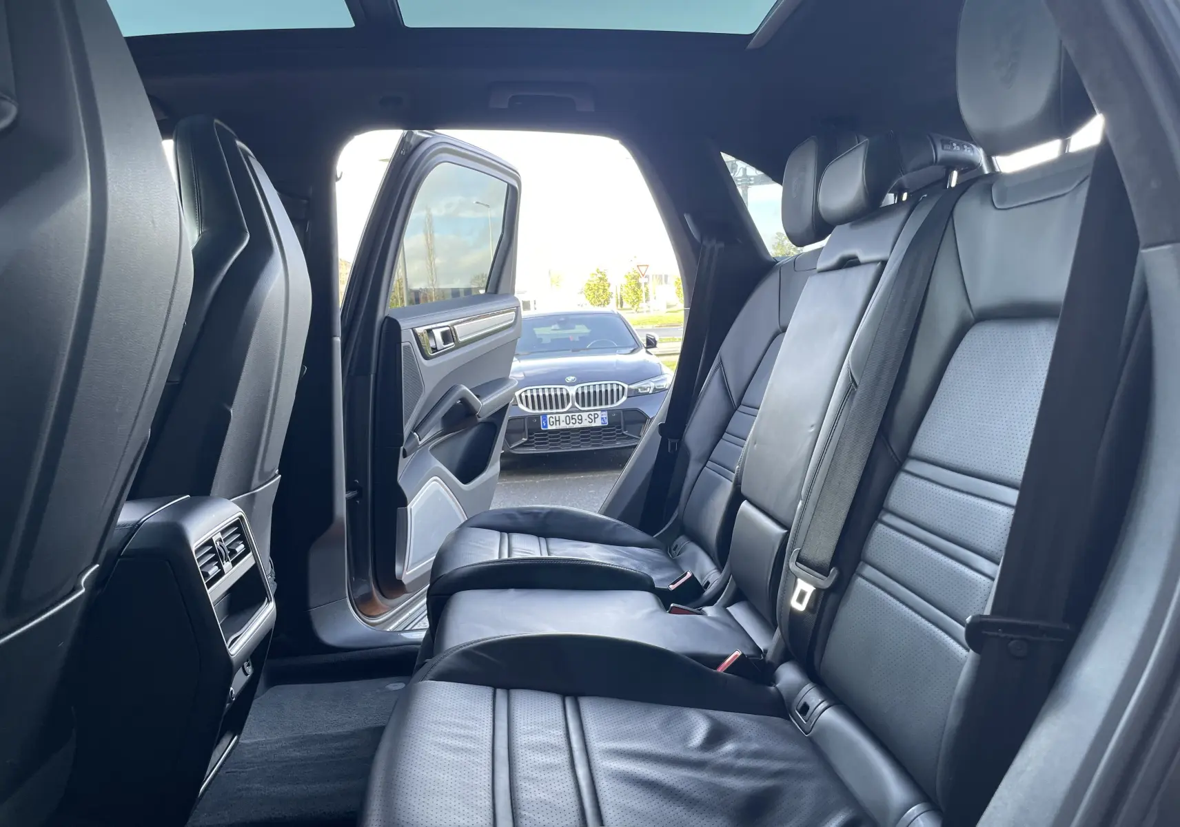 Vue intérieure arrière du Porsche Cayenne E-Hybrid 2018 avec portes ouvertes et sièges en cuir noir visibles.