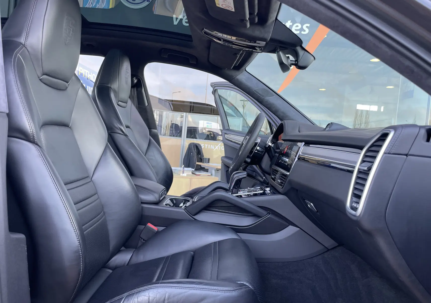 Vue intérieure côté gauche du Porsche Cayenne E-Hybrid 2018 avec sièges cuir noirs et tableau de bord moderne.