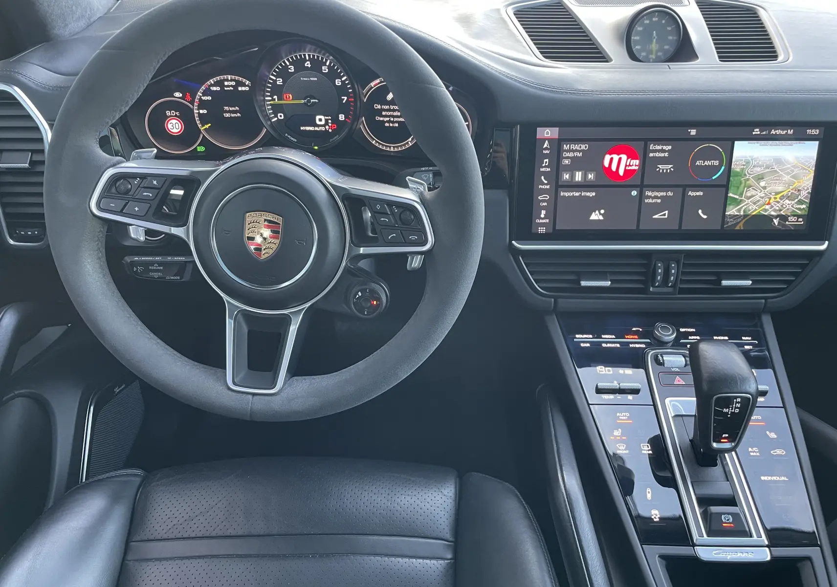 Vue intérieure centrée sur le volant et la console centrale du Porsche Cayenne E-Hybrid 2018 en cuir noir.