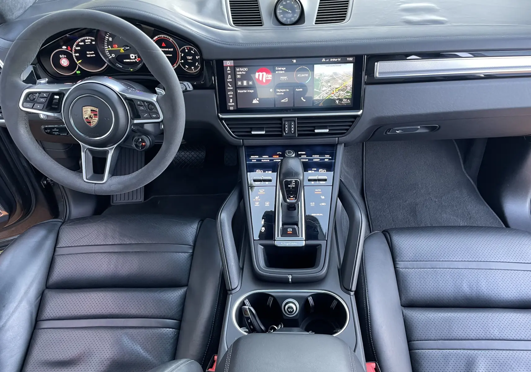 Vue intérieure frontale du Porsche Cayenne E-Hybrid 2018 avec tableau de bord numérique et sellerie cuir noire.