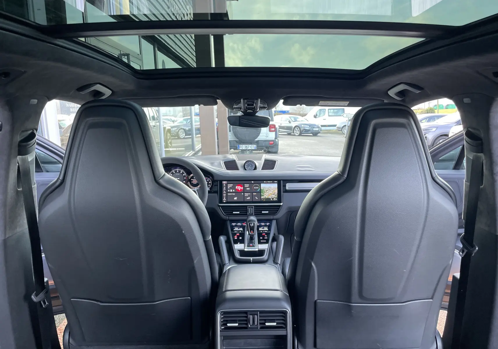 Vue intérieure arrière du Porsche Cayenne E-Hybrid 2018, montrant les sièges noirs, le toit panoramique et le tableau de bord moderne.