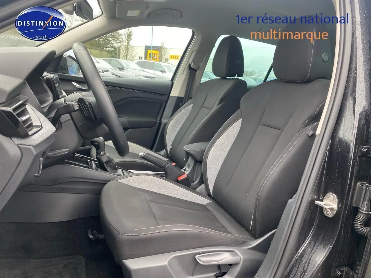 Vue intérieure côté gauche montrant les sièges avant noirs et gris du Skoda Kamiq 2025 avec volant multifonction.