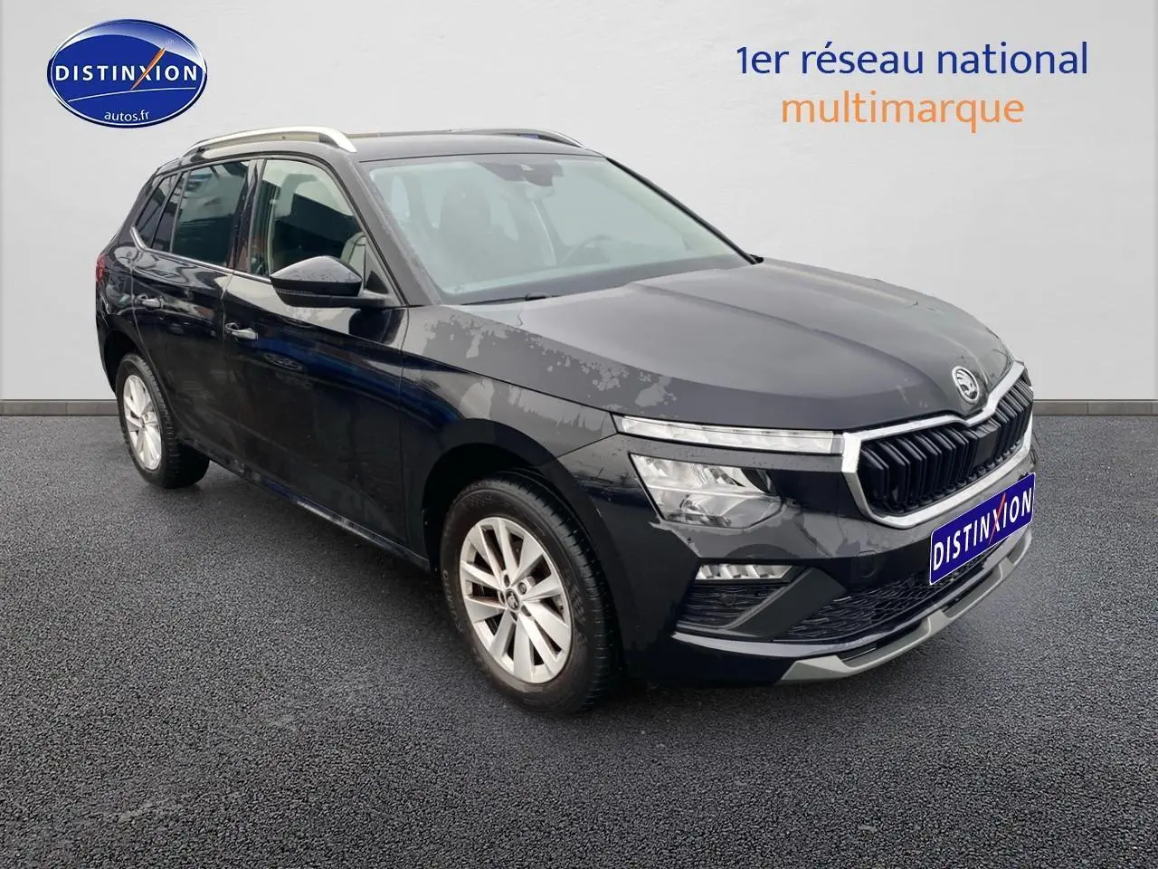 Vue 3/4 avant d'un Skoda Kamiq noir 2025 avec calandre chromée et jantes alu sur sol gris.