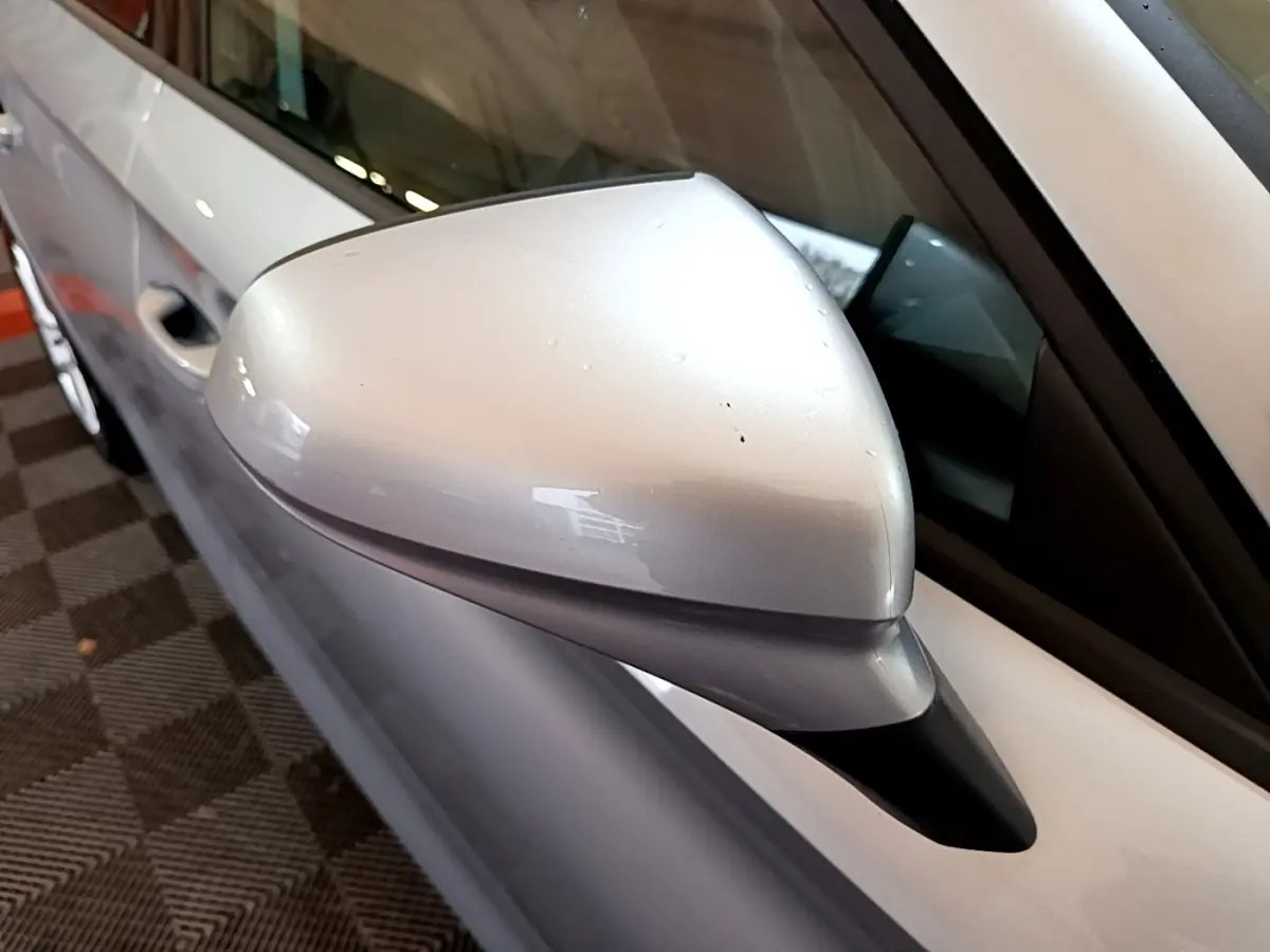 Gros plan sur le rétroviseur côté conducteur gris clair du SEAT Leon 2022, avec partie de la portière visible en gris foncé.