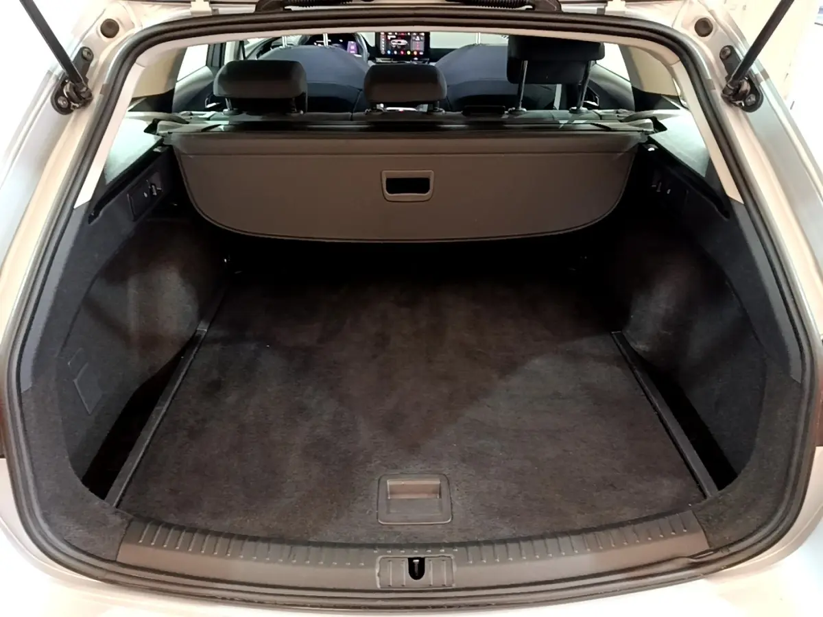 Coffre ouvert vu de l'arrière d'une SEAT Leon gris foncé, montrant l'espace de chargement et la tablette cache-bagages.