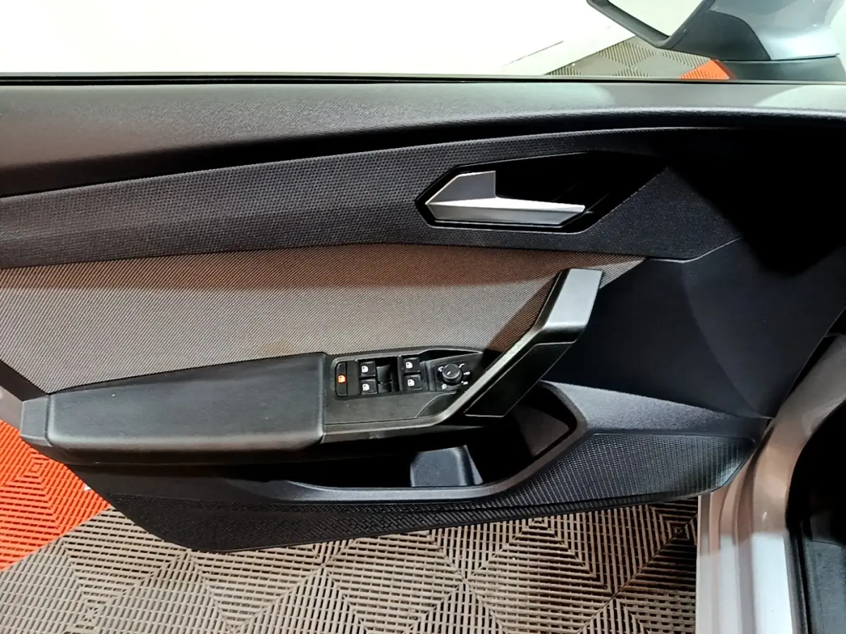 Vue rapprochée de la porte avant gauche grise du SEAT LEON 2022, avec commandes électriques et poignée noire.