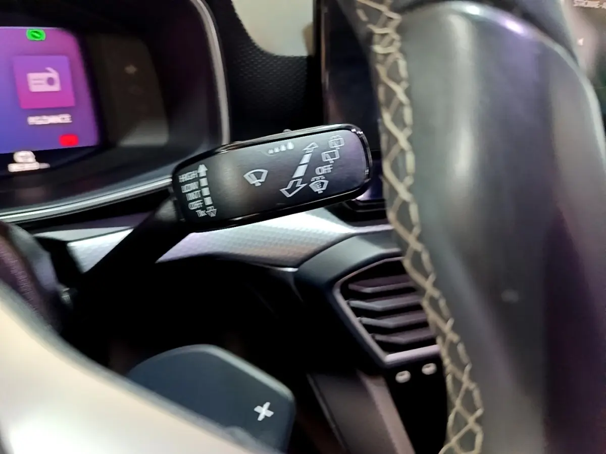 Gros plan sur la commande des essuie-glaces du SEAT Leon 2022, intérieur noir avec volant en cuir surpiqué.