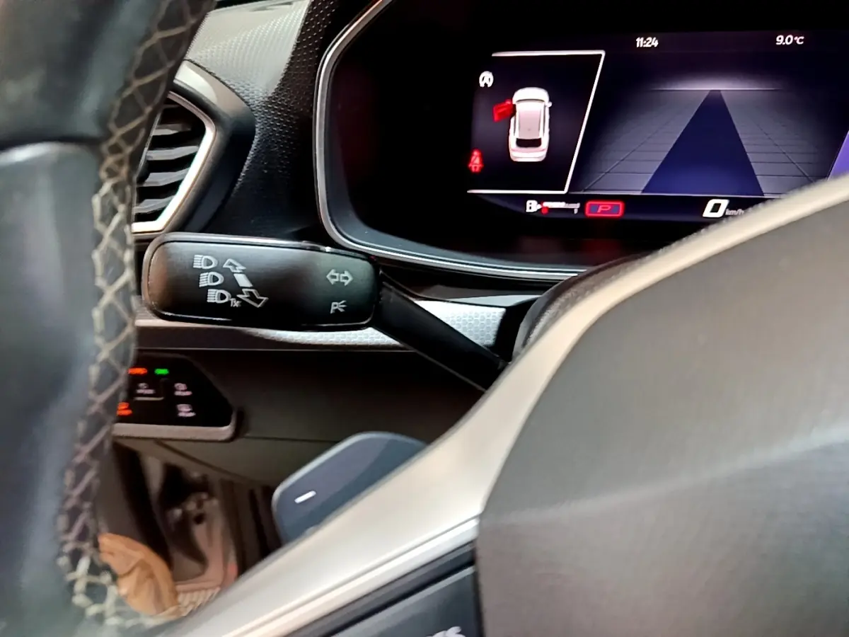 Gros plan sur le tableau de bord numérique et la commande de clignotants du SEAT Leon gris foncé, intérieur moderne.