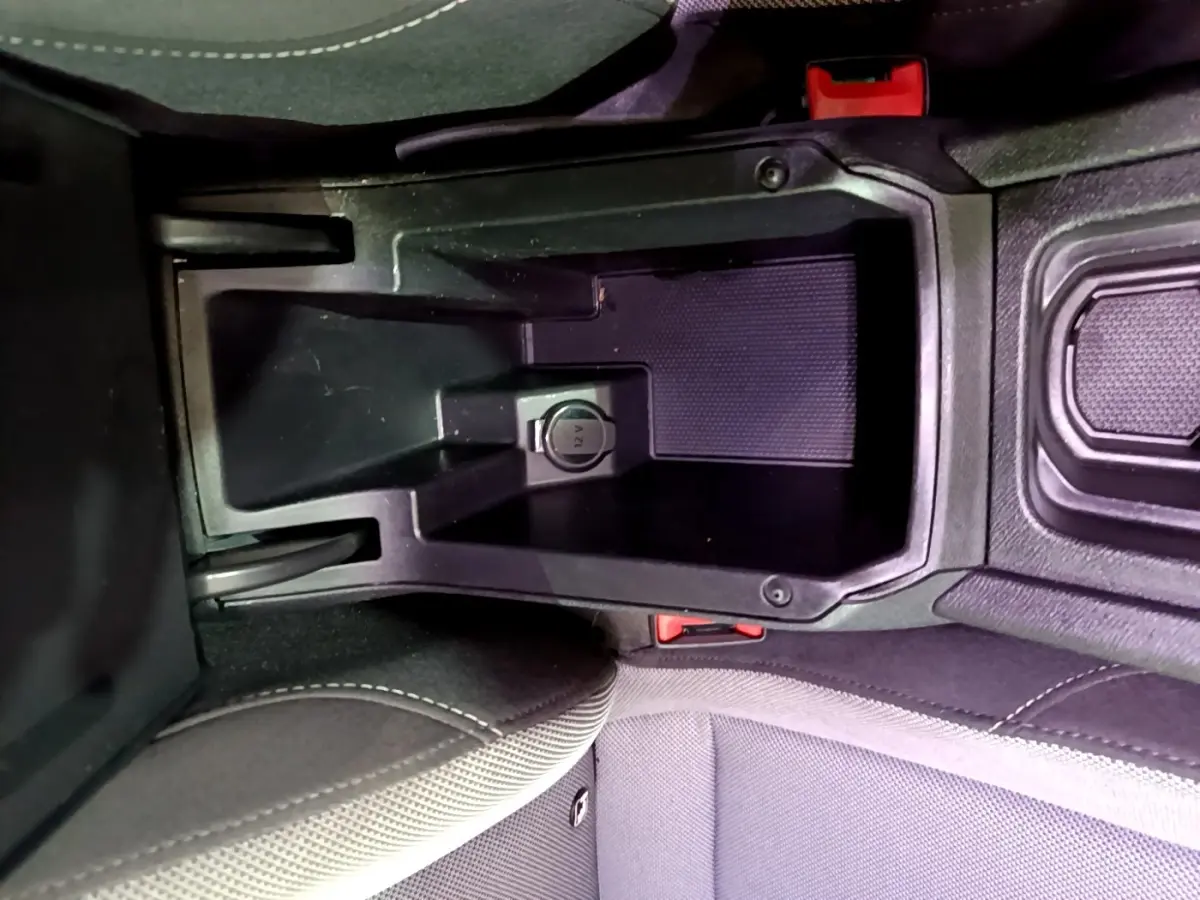 Vue rapprochée de la console centrale intérieure du SEAT Leon gris foncé, montrant la prise 12V et les sièges tissu.