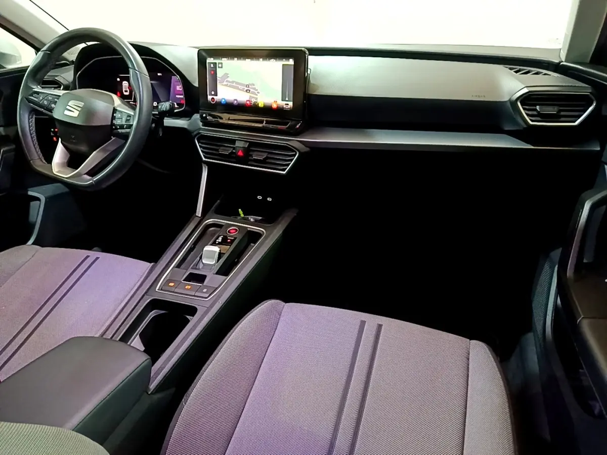 Intérieur avant du SEAT Leon 2022, vue côté conducteur, tableau de bord noir avec écran tactile et volant cuir.