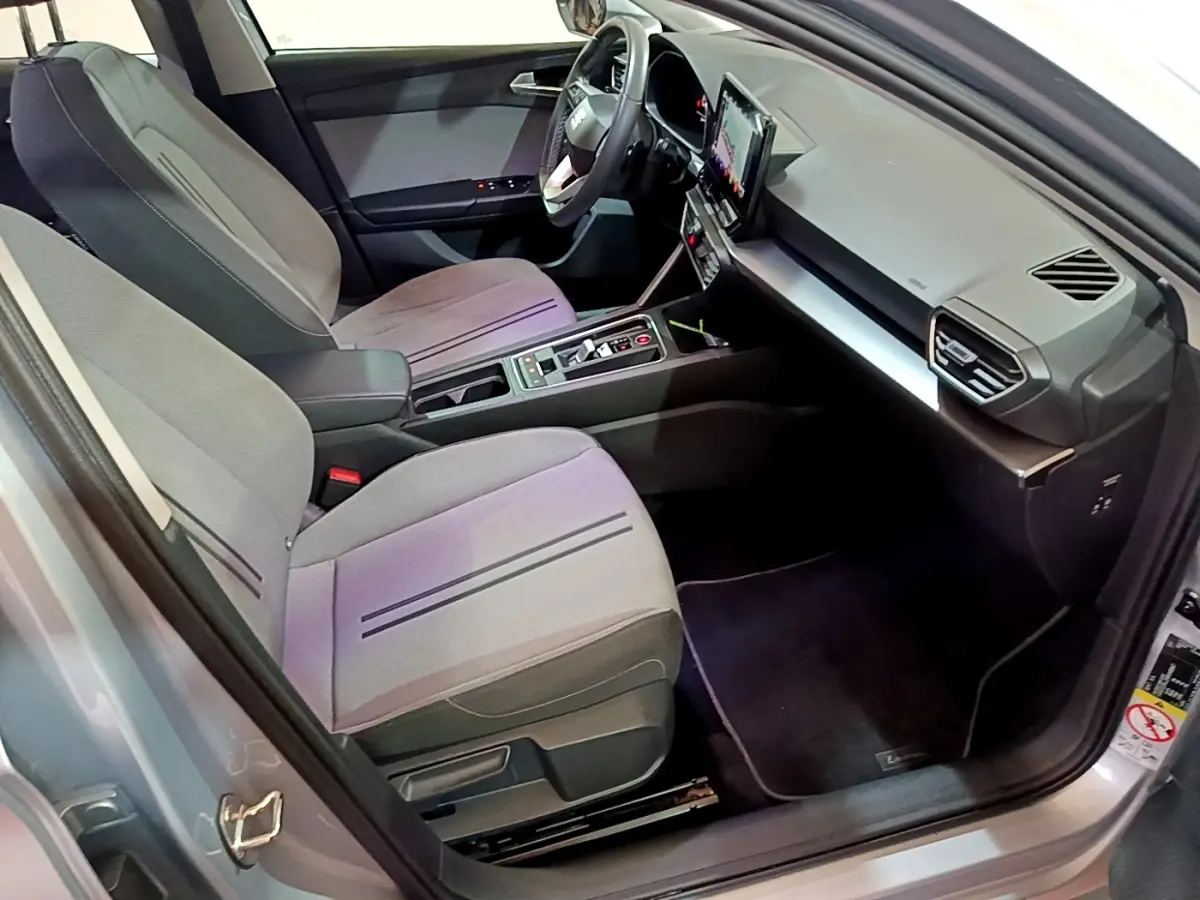 Intérieur avant de la SEAT Leon gris foncé, vue côté conducteur, avec écran tactile central et sièges tissu gris.