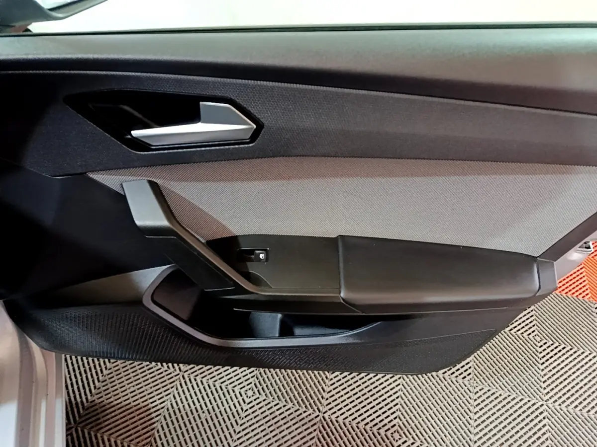 Vue intérieure côté gauche de la porte avant gris foncé de la SEAT LEON 2022 avec poignée argentée et accoudoir noir.