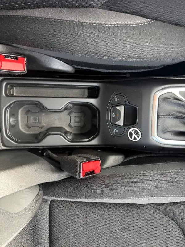 Vue plongeante sur la console centrale noire du Jeep Renegade 2023, avec porte-gobelets et bouton frein de stationnement.