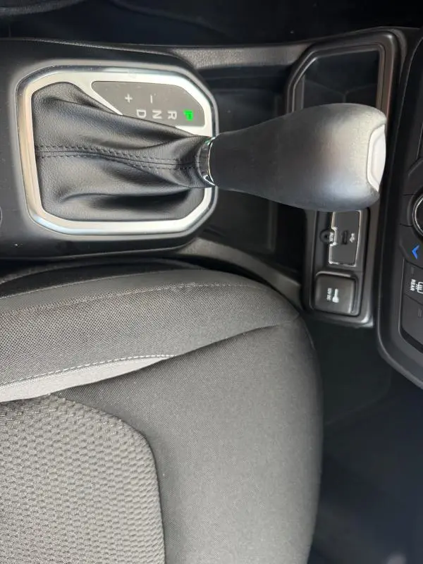 Vue rapprochée de la commande de boîte automatique noire et du siège conducteur en tissu gris du Jeep Renegade 2023.