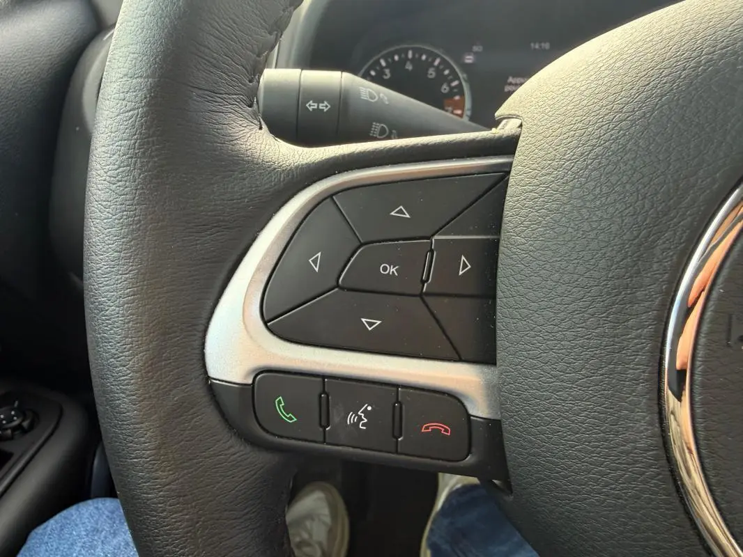 Gros plan sur les commandes gauche du volant cuir du Jeep Renegade bleu 2023 avec boutons de téléphone et navigation.