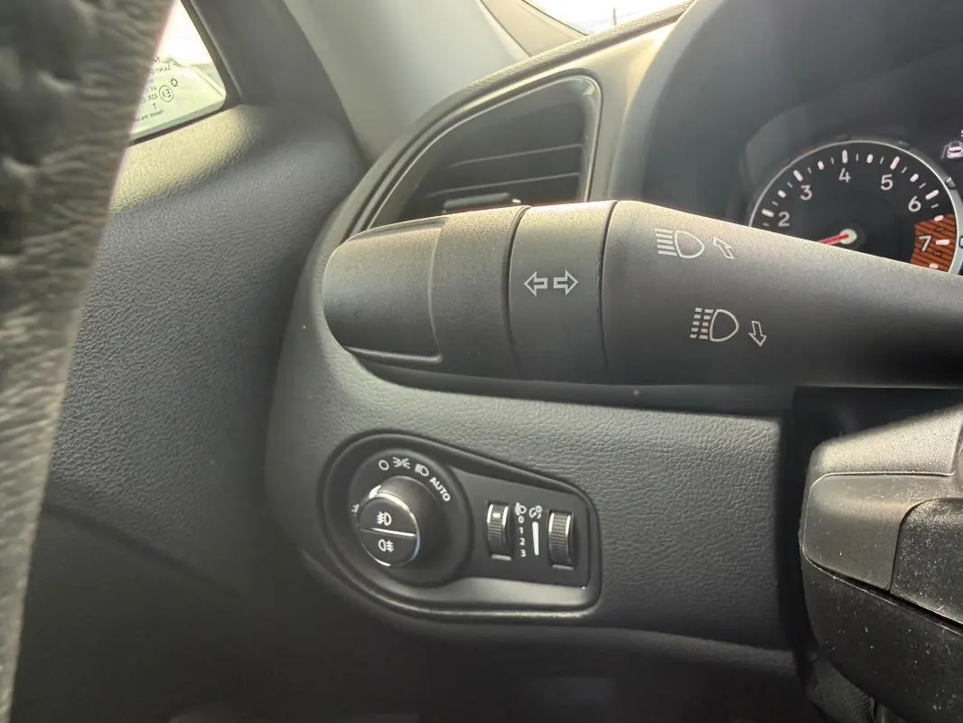Gros plan sur la commande des phares et clignotants à gauche du volant dans l’habitacle noir du Jeep Renegade bleu 2023.