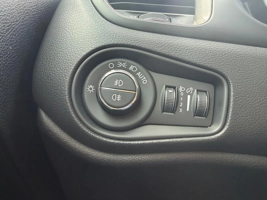 Gros plan sur les commandes d’éclairage noires du tableau de bord intérieur d’une Jeep Renegade bleu 2023.