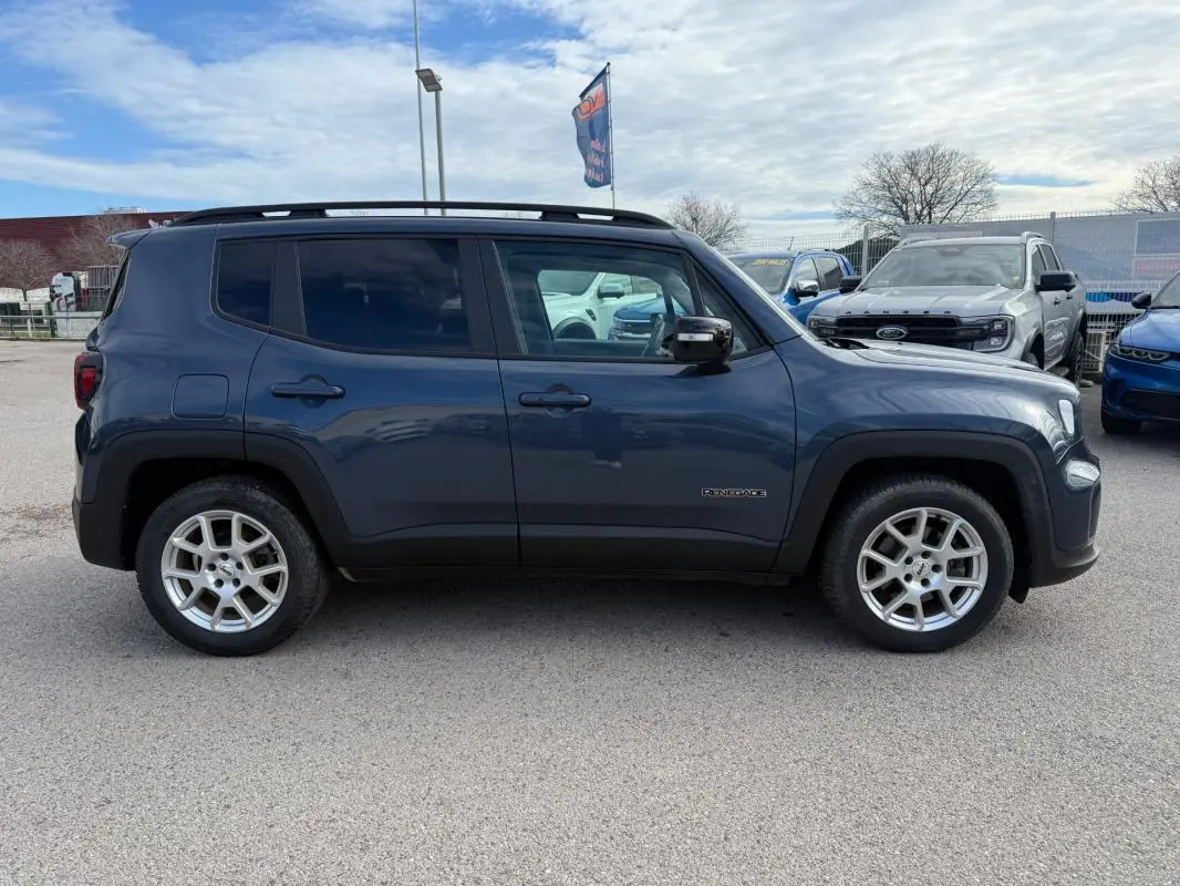 Vue de profil côté gauche d'un Jeep Renegade bleu 2023 avec barres de toit et jantes alliage 17 pouces.