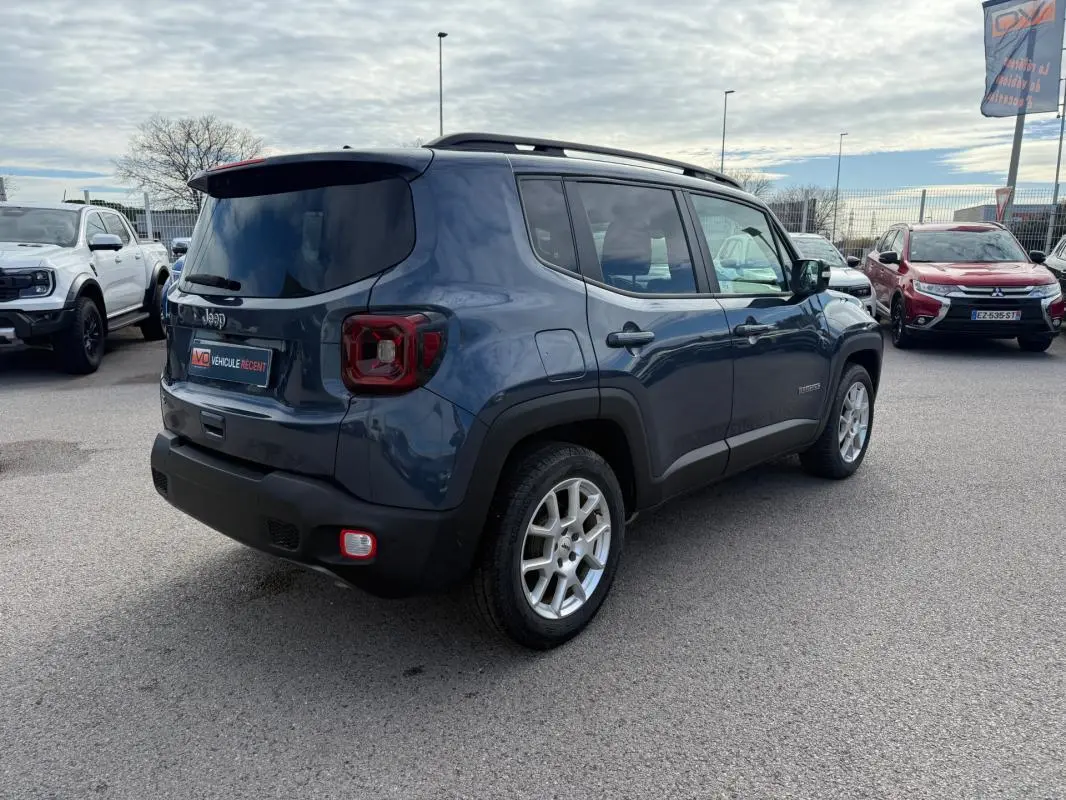 Vue 3/4 arrière droite d’un Jeep Renegade bleu 2023 avec barres de toit et jantes alliage 17 pouces.