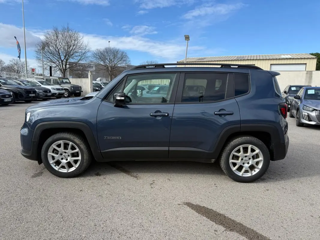Vue de profil côté gauche d'un Jeep Renegade bleu 2023 avec barres de toit et jantes alliage 17 pouces.
