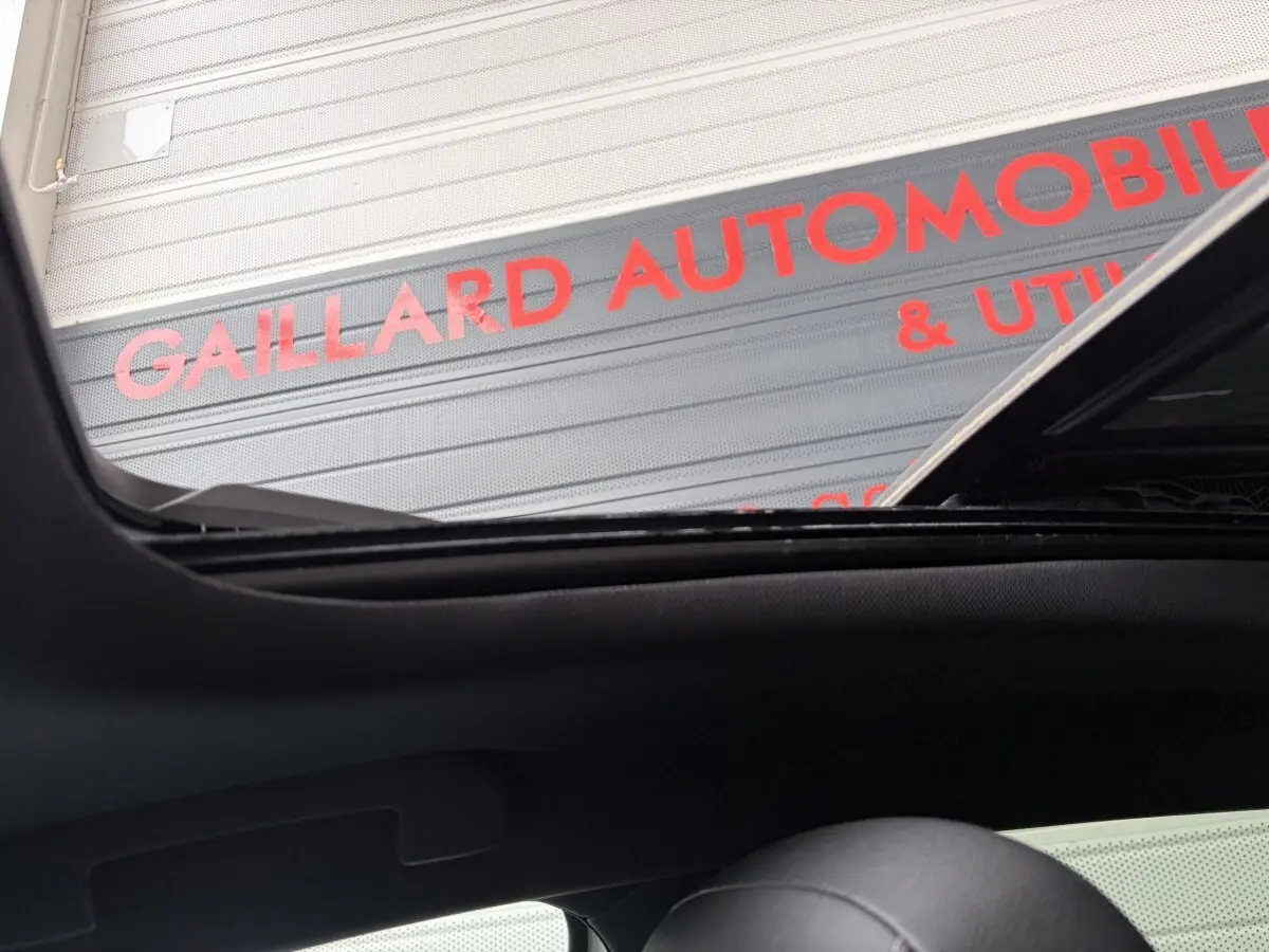 Vue intérieure du toit ouvrant ouvert de l’Opel Astra blanc, avec vue partielle sur l’appui-tête noir.