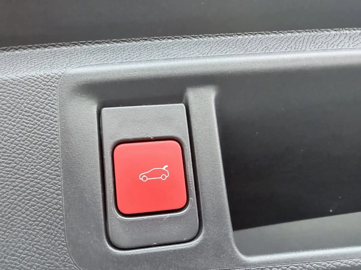 Gros plan sur le bouton rouge d'ouverture du coffre dans l'habitacle de l'Opel Astra 2024.