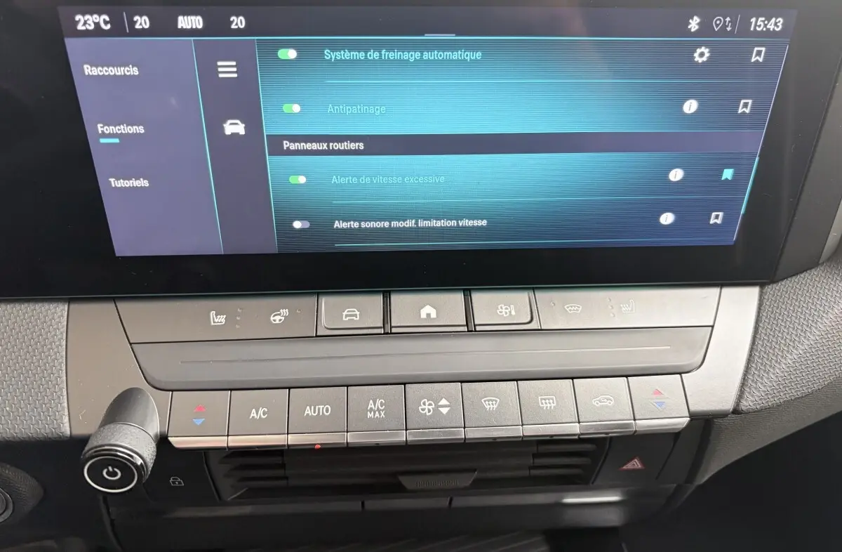 Vue rapprochée de la console centrale et écran tactile de l’Opel Astra blanc, affichant les réglages d’aide à la conduite.
