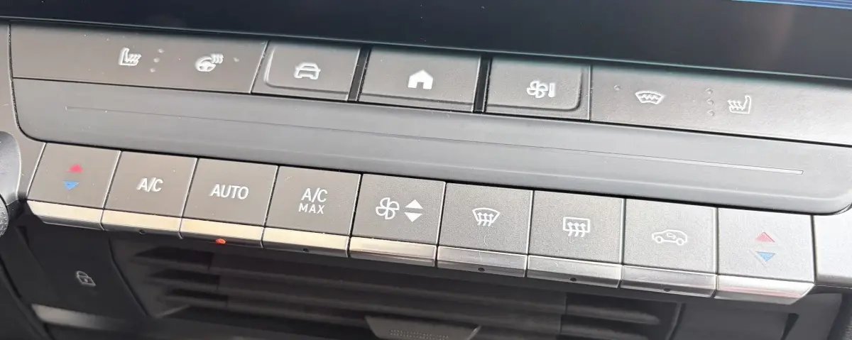 Vue rapprochée du tableau de bord de l’Opel Astra blanc 2024, montrant les commandes climatisation et sièges chauffants.