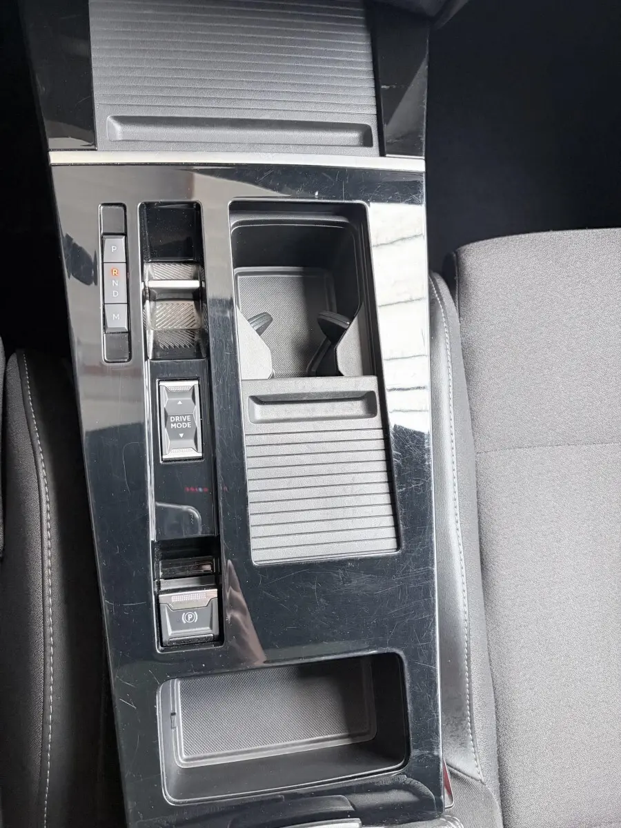 Vue plongeante sur la console centrale noire brillante de l'Opel Astra 2024 avec sélecteur de boîte auto et rangement.