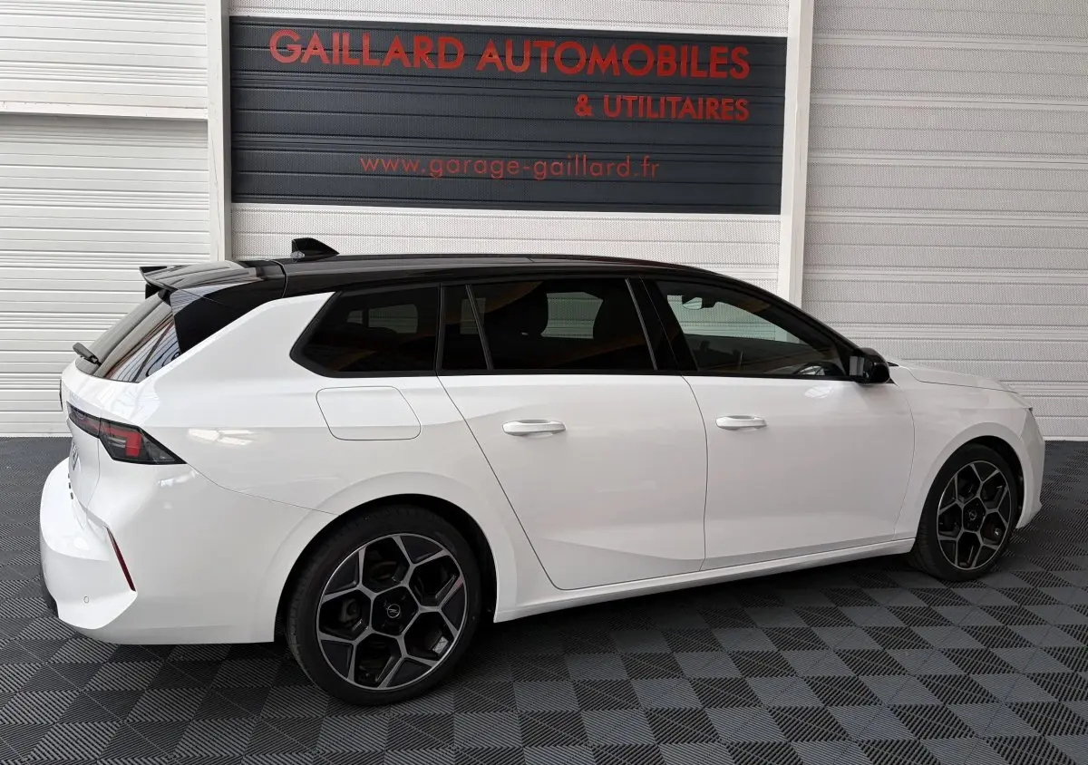 Vue de profil droit d'une Opel Astra blanche break avec toit noir et jantes alliage au design hexagonal.